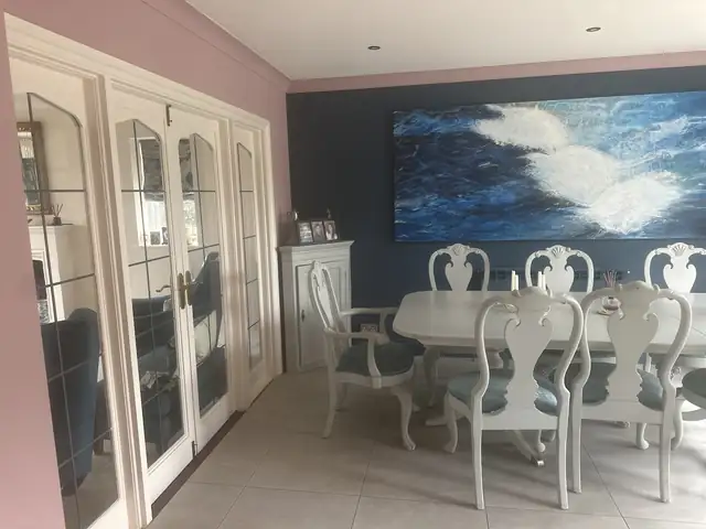 Dining room with soft pink walls, a navy feature wall and white French doors