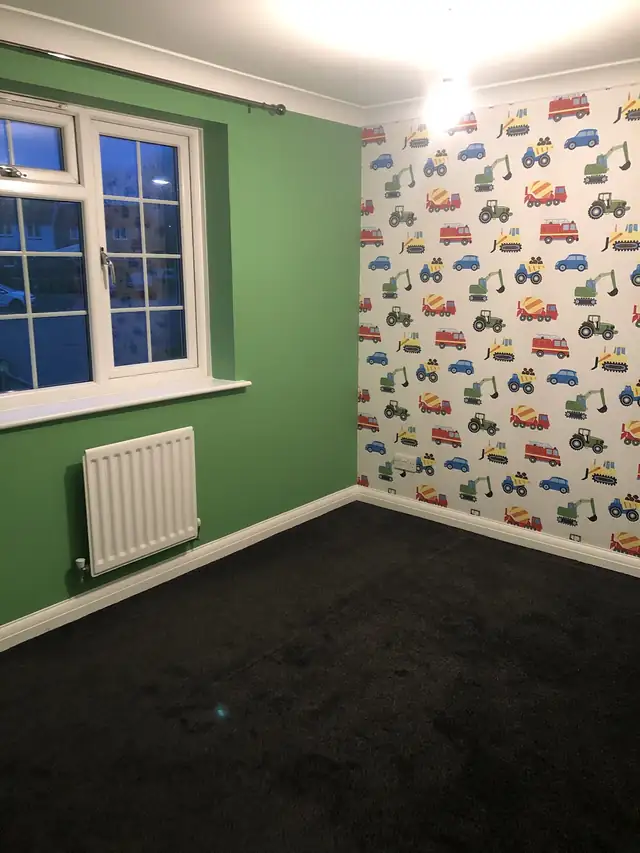 Child's bedroom with green walls and a digger and truck feature wallpaper