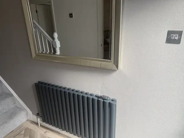 Smooth freshly painted hallway wall with a grey column radiator